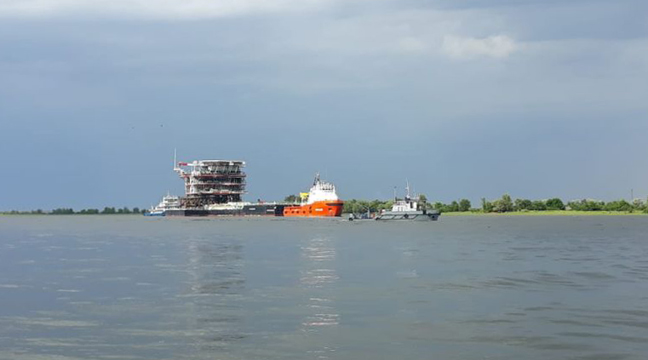 Towing convoy with upper part of drilling platform facility performs a voyage on the Volga-Caspian Marine Shipping Canal